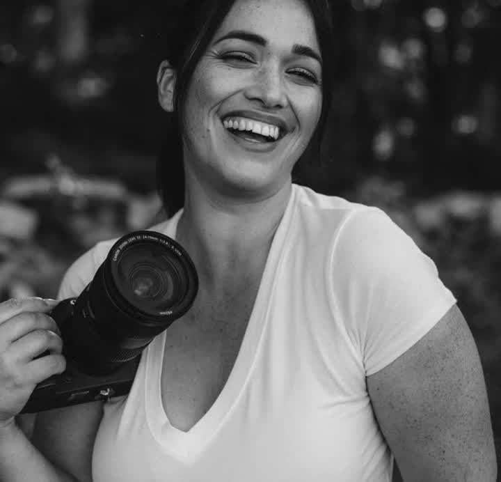 Ana Rousseau, Cape Coral newborn and family photographer, laughing with her camera in black and white