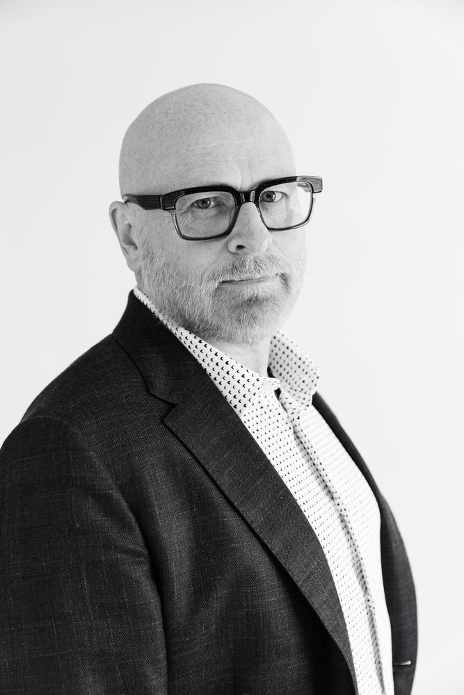 Black and white close portrait of a man in a blazer against white
