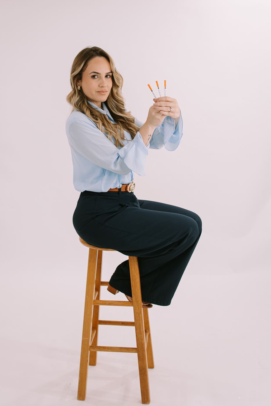 Personal branding portrait of a professional in a light blue shirt seated on a stool, Cape Coral studio