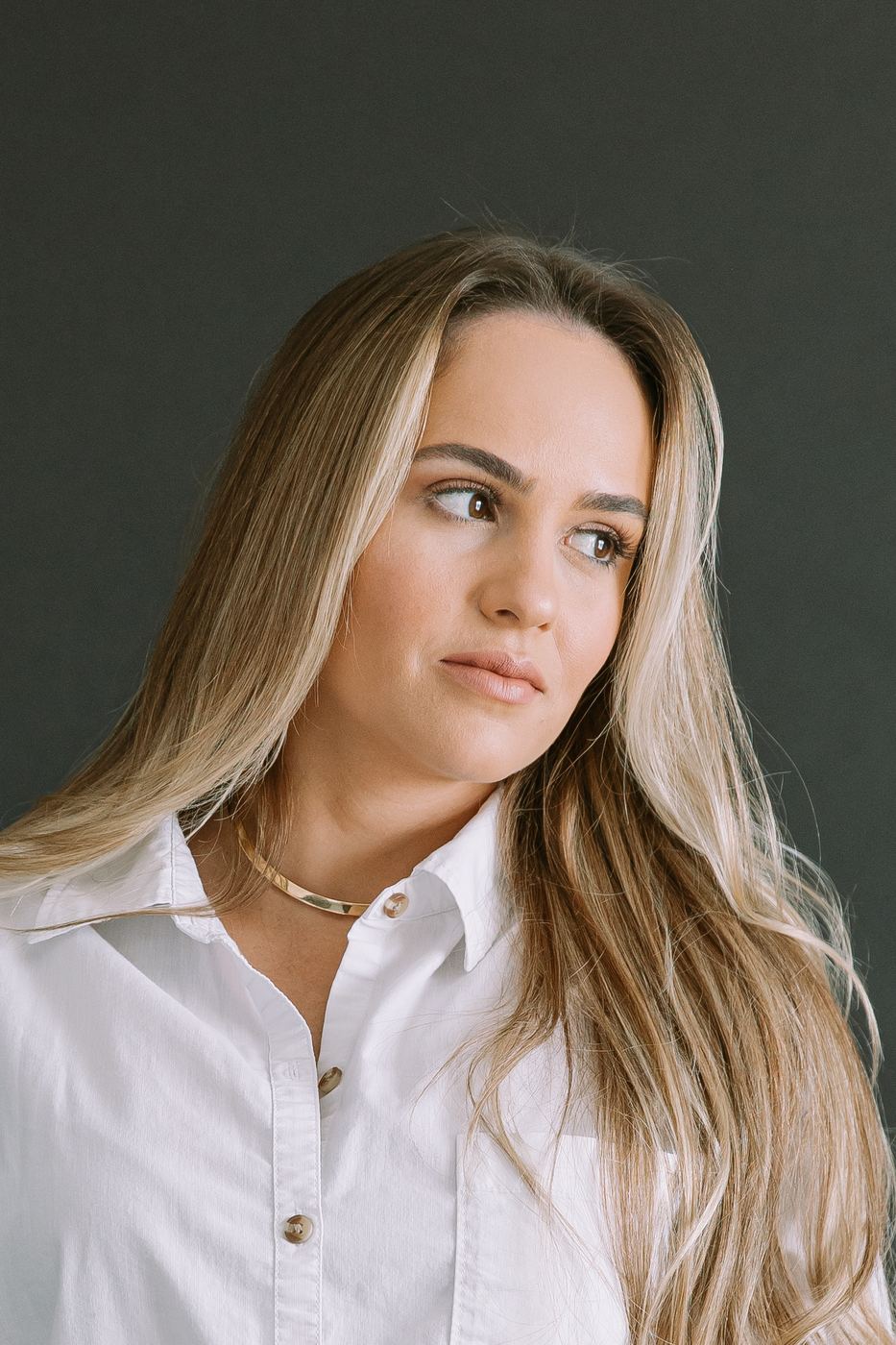 Editorial branding close-up in a white shirt with windswept hair, soft studio light