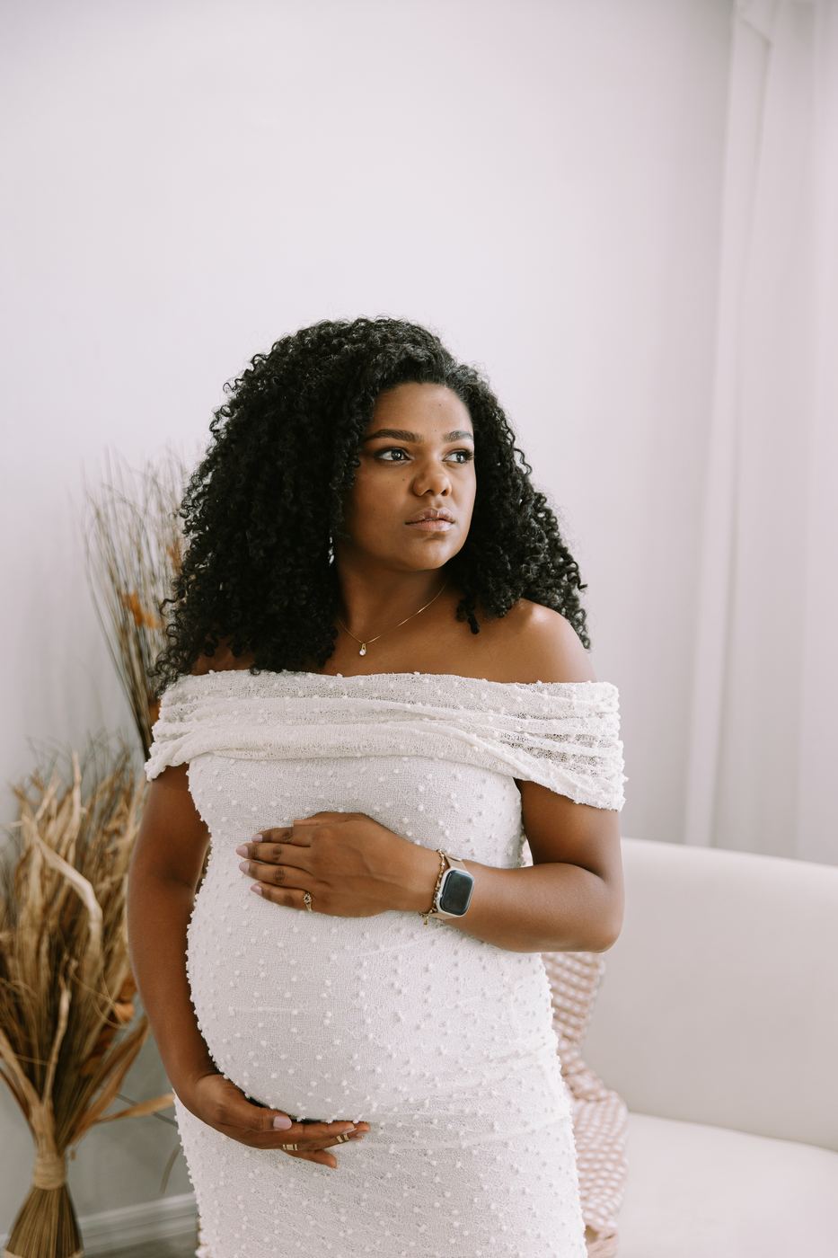 Expecting mother in a white off-shoulder gown with pampas grass, studio maternity session in Cape Coral