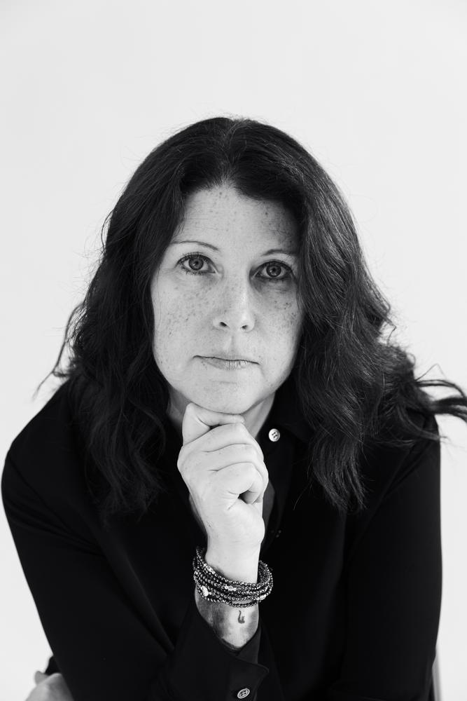 Black and white portrait of a woman with a direct gaze against a bright white backdrop