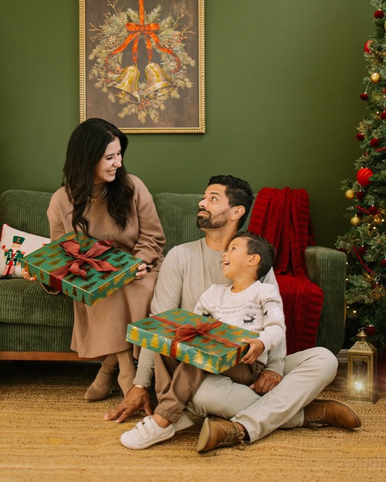 Family opening Christmas gifts together on the green velvet couch at the Cape Coral studio